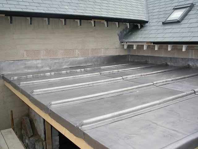 Rolled lead flat roof with welted seams and lead flashing against slate and blockwork