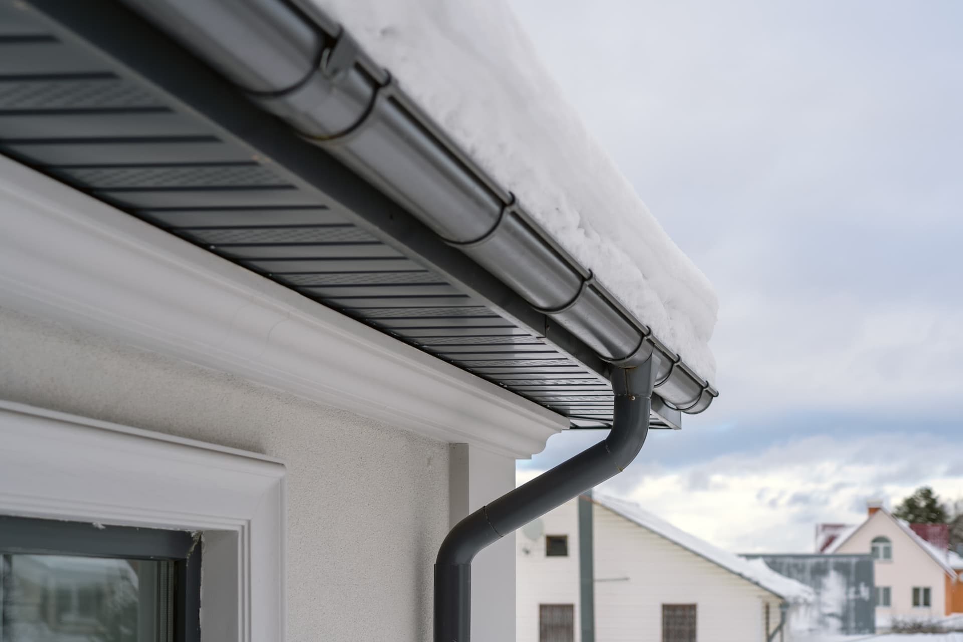 New grey guttering, fascia, soffit and downpipe fitted along a house eaves